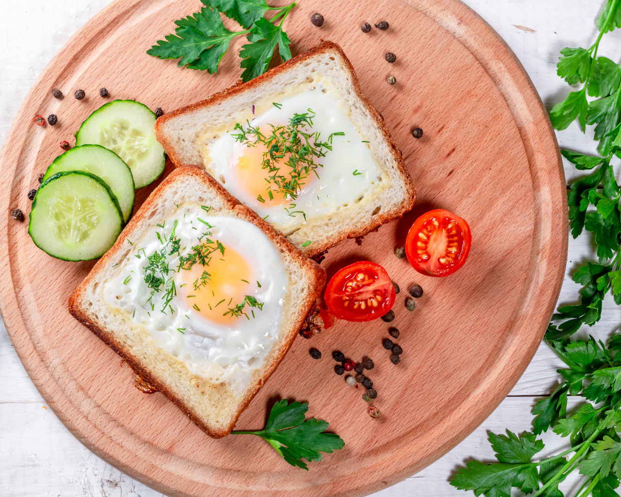 Яичница в хлебе на доске с помидорами, огурцами и петрушкой