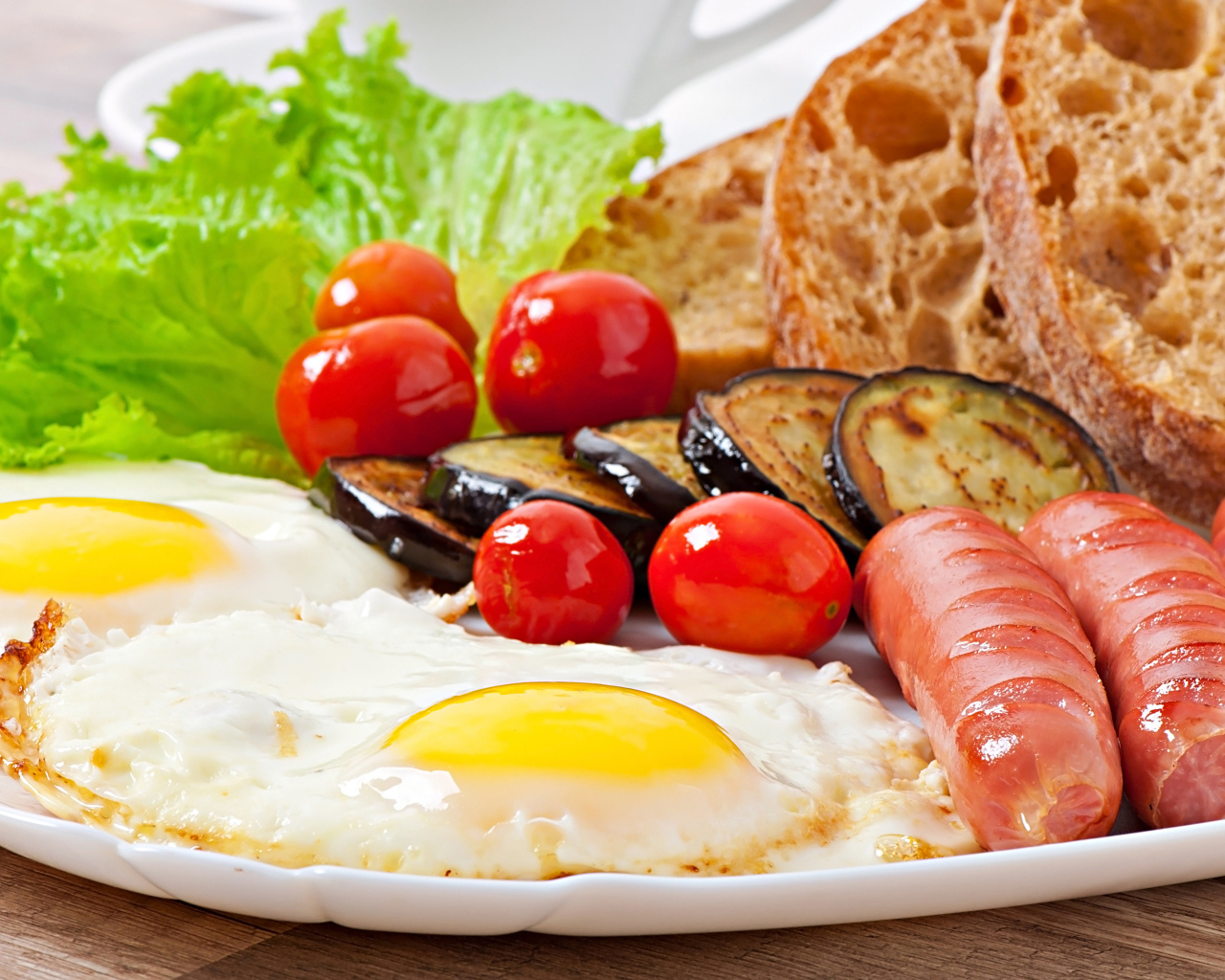 Яичница на тарелке с сосисками, овощами и хлебом