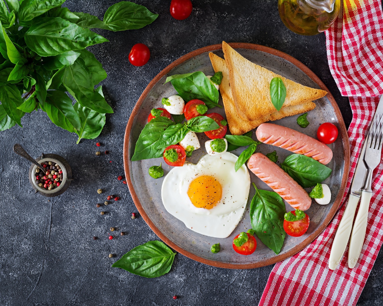 Яичница на тарелке с помидорами, гренками, сыром, сосисками и зеленью базилика