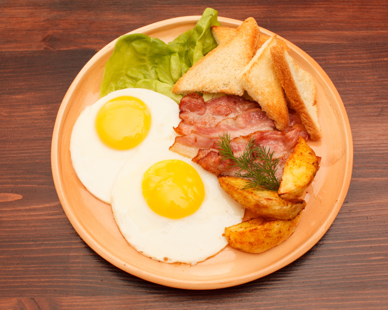 Яичница с беконом, картофелем фри и гренками на столе 