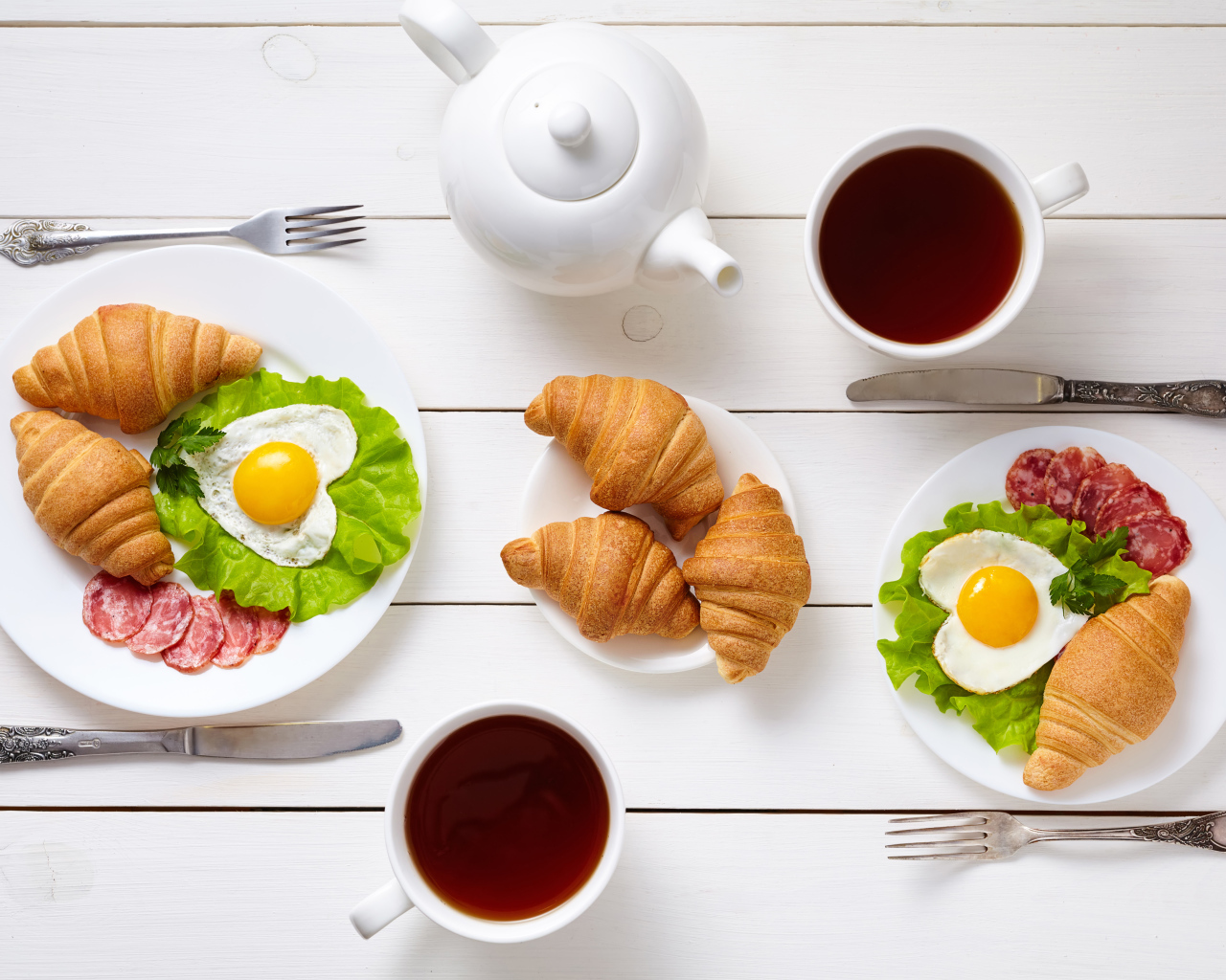 Яичница с колбасой и круассанами на столе чаем 
