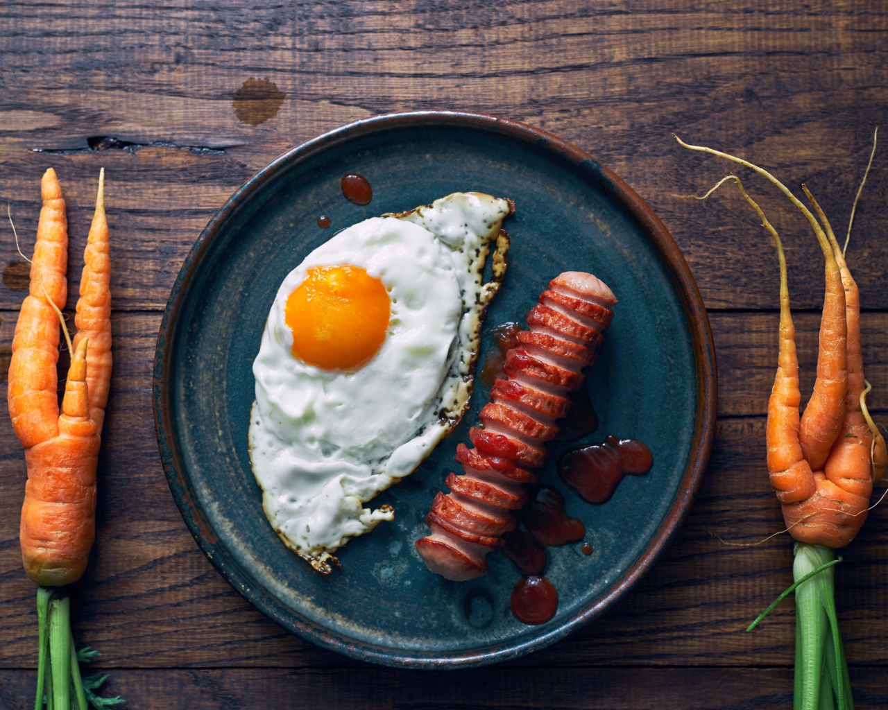 Яичница с сосиской на столе с морковью 