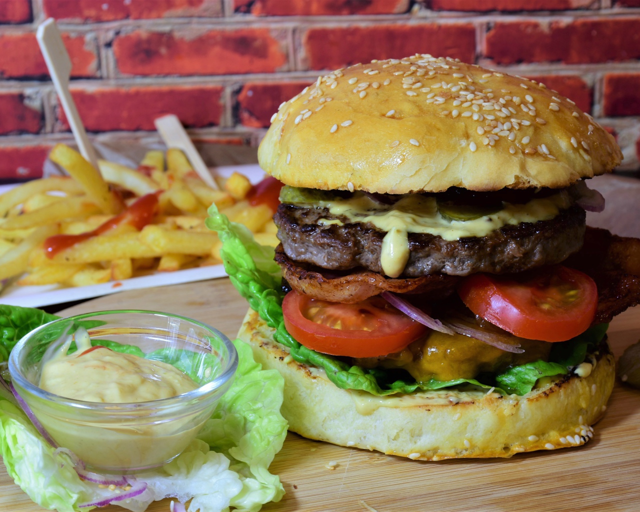 Гамбургер с беконом на столе с соусом и картофелем фри