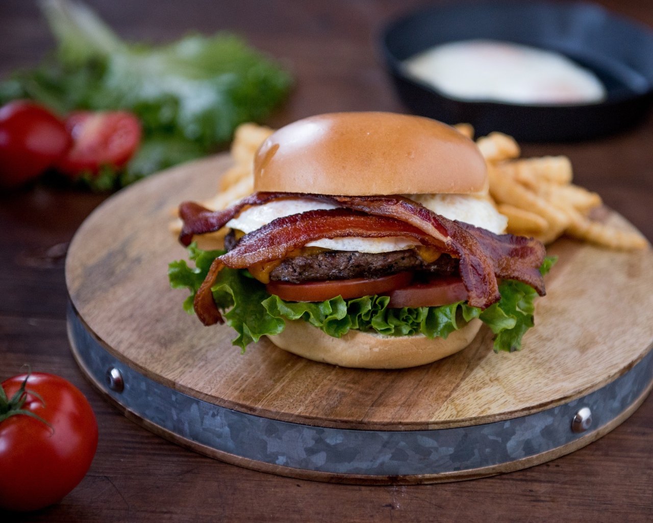 Гамбургер с беконом на столе с овощами