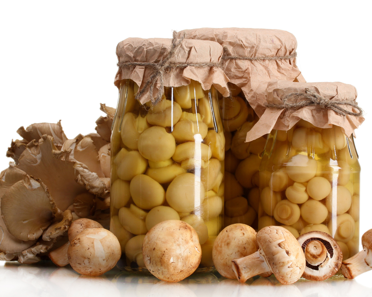 Маринованные шампиньоны в банках на белом фоне со свежими