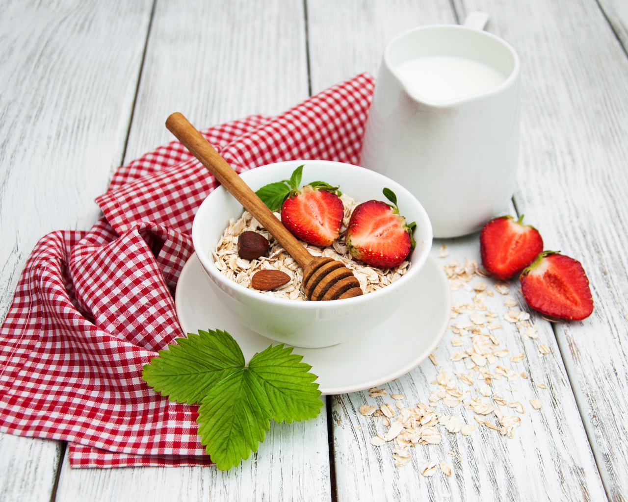 Овсяная каша на столе с молоком и клубникой