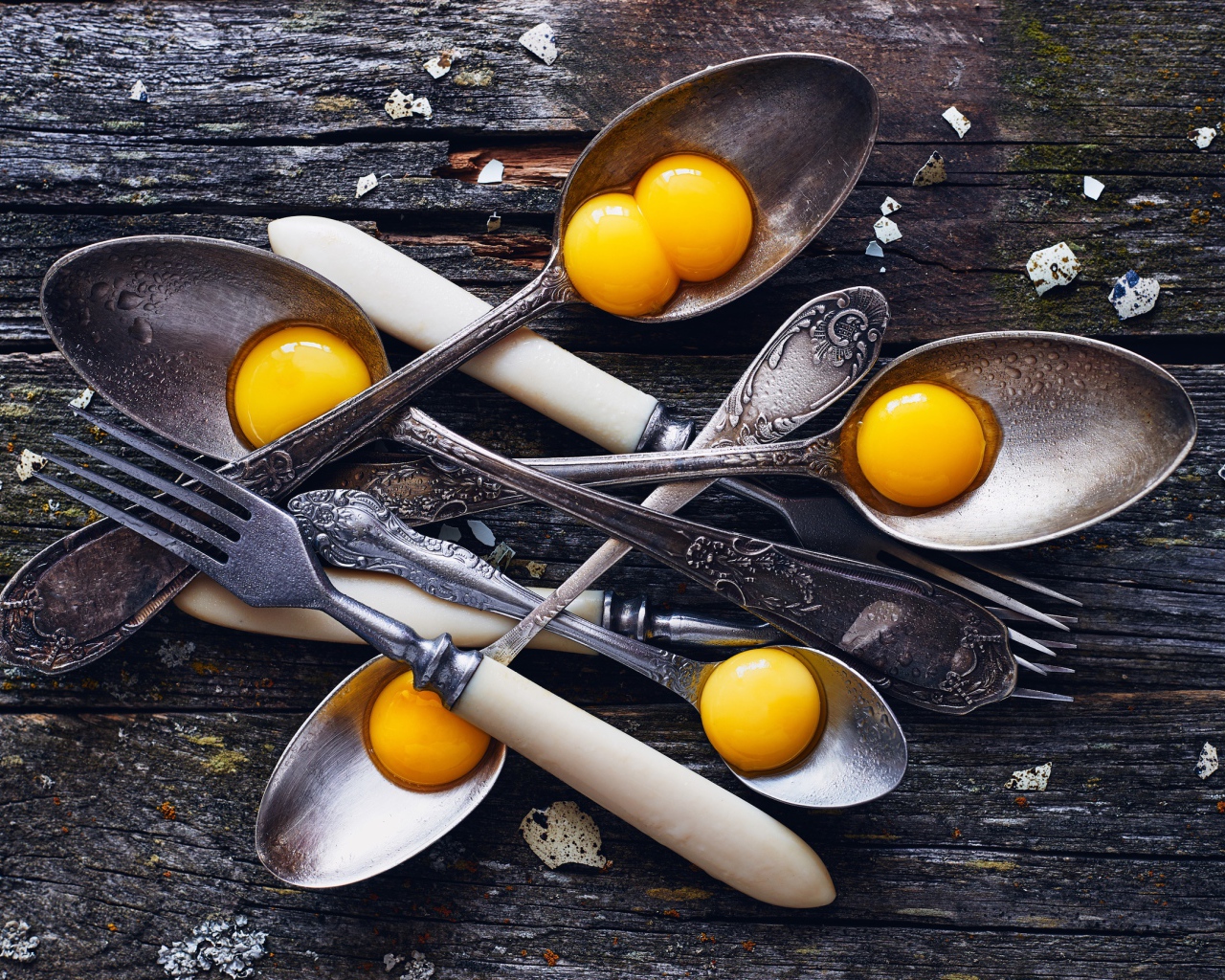 Старые ложки с желтками на деревянном столе