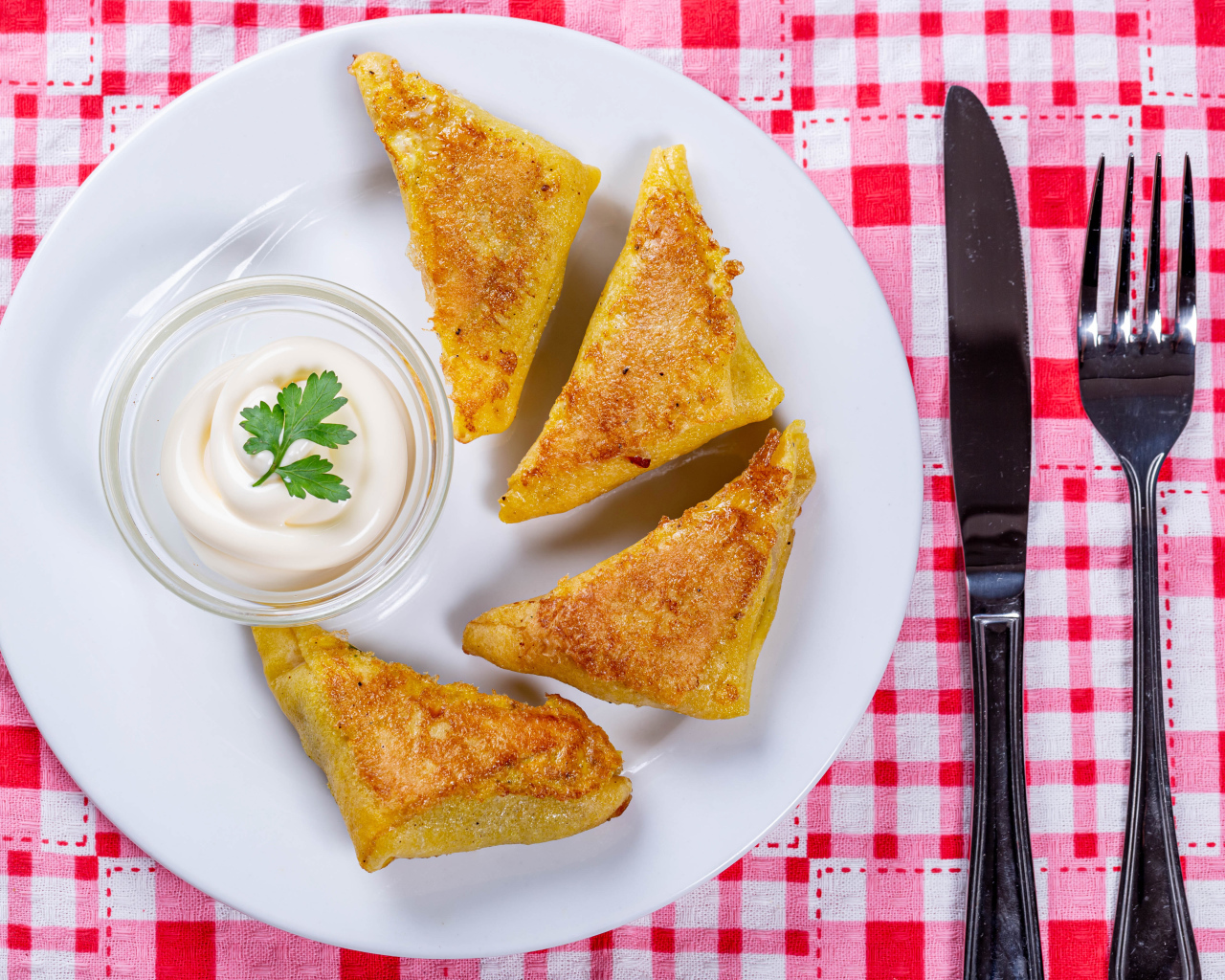 Блинчики со сметаной на столе со столовыми приборами 