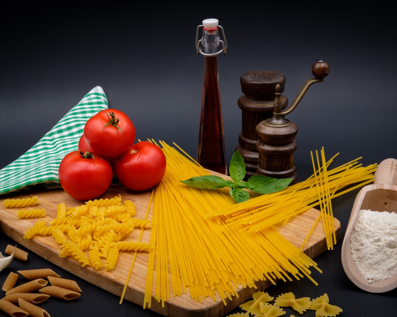 Макаронные изделия на столе с мукой, помидорами и специями