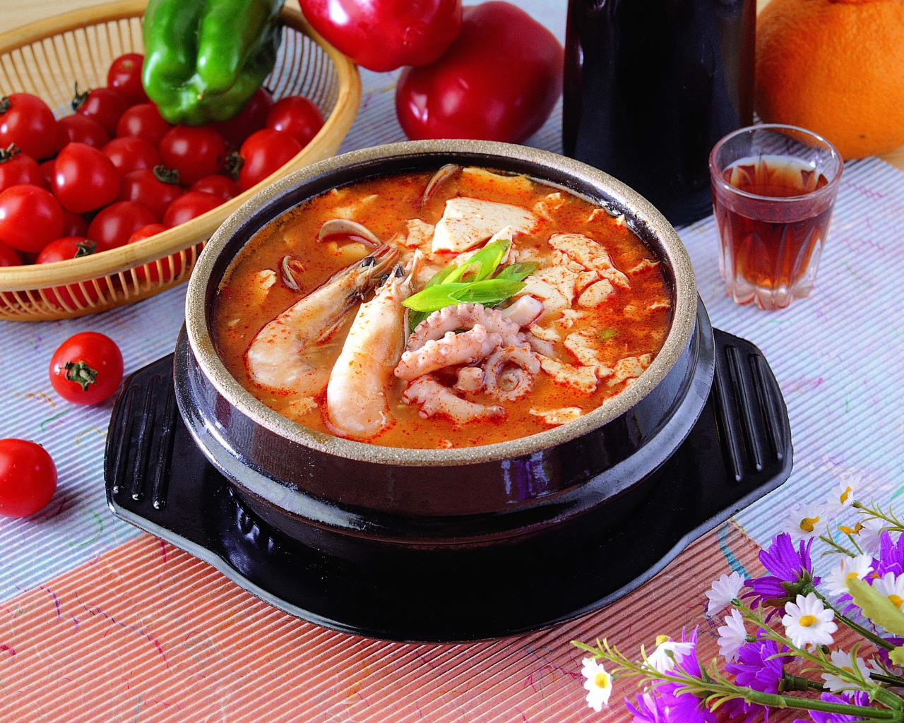 Тарелка красного супа с морепродуктами на столе с овощами 