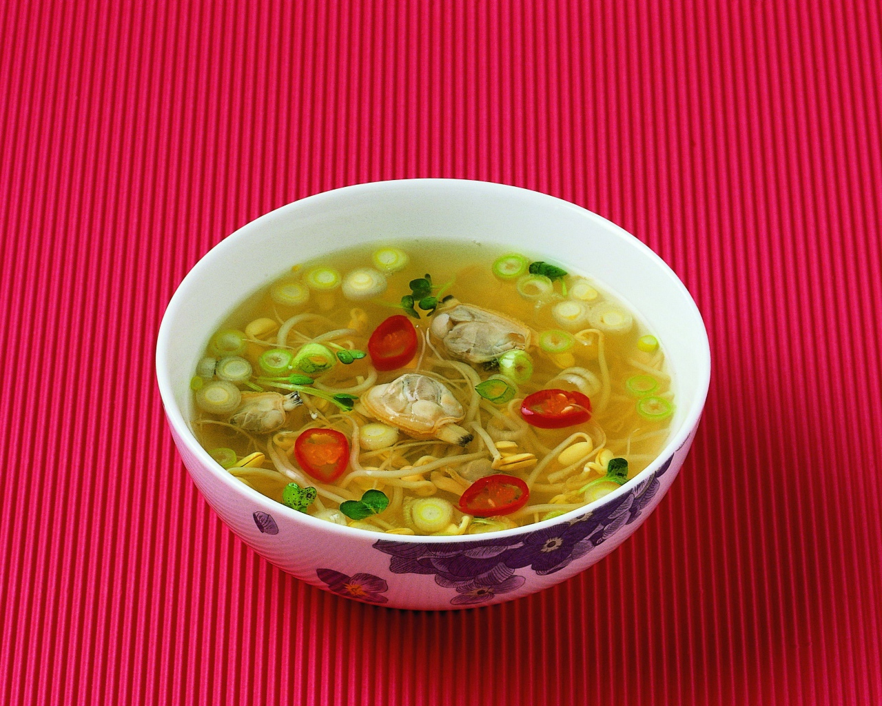 Тарелка супа с морепродуктами на красном фоне