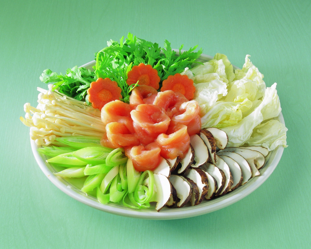 Тарелка с овощами и красной рыбой на зеленом фоне