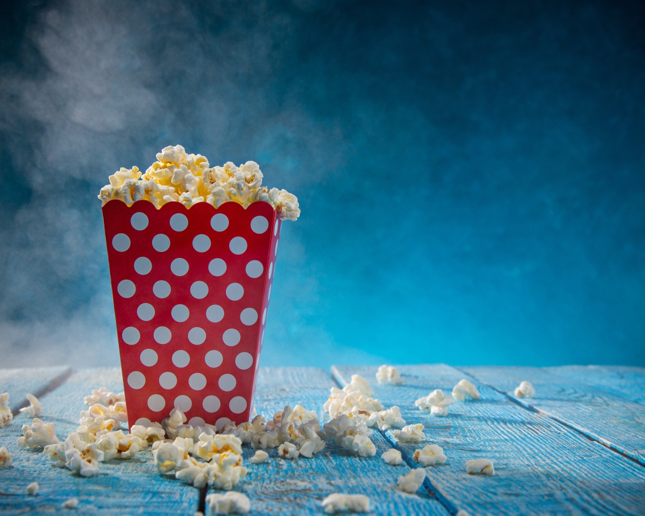 Попкорн в картонном пакете на голубом столе 