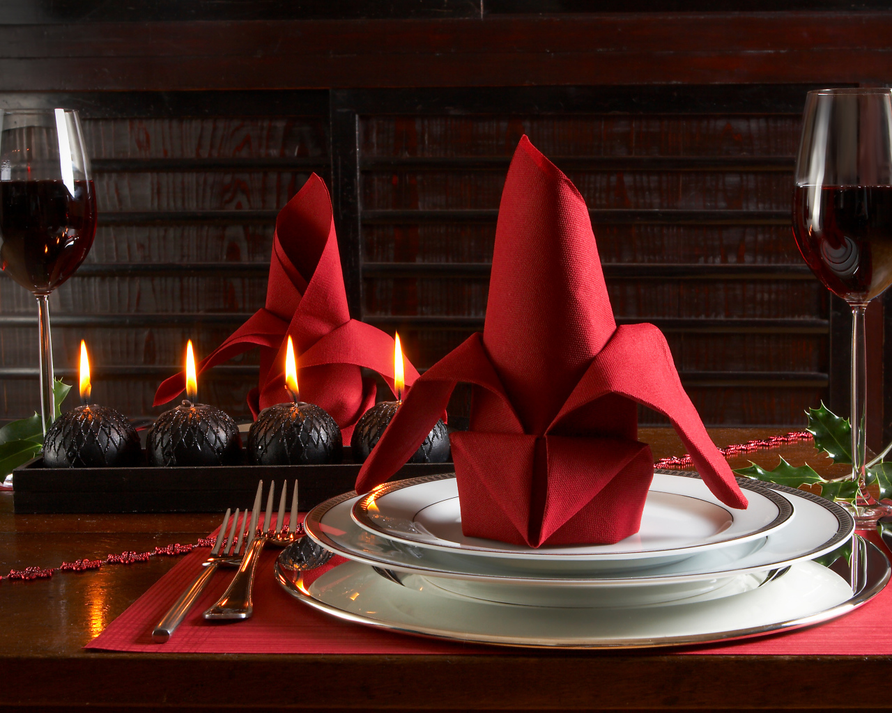 Красная салфетка на тарелке на столе с бокалами вина и свечами