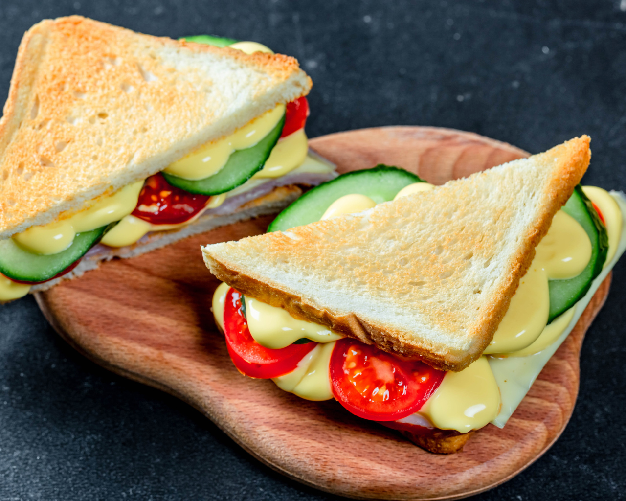 Сэндвич с сыром, помидорами и огурцами на столе