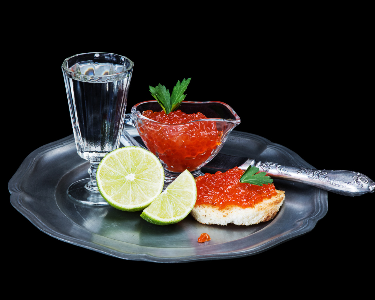 Бутерброды с красной икрой на подносе с рюмкой водки и лаймом