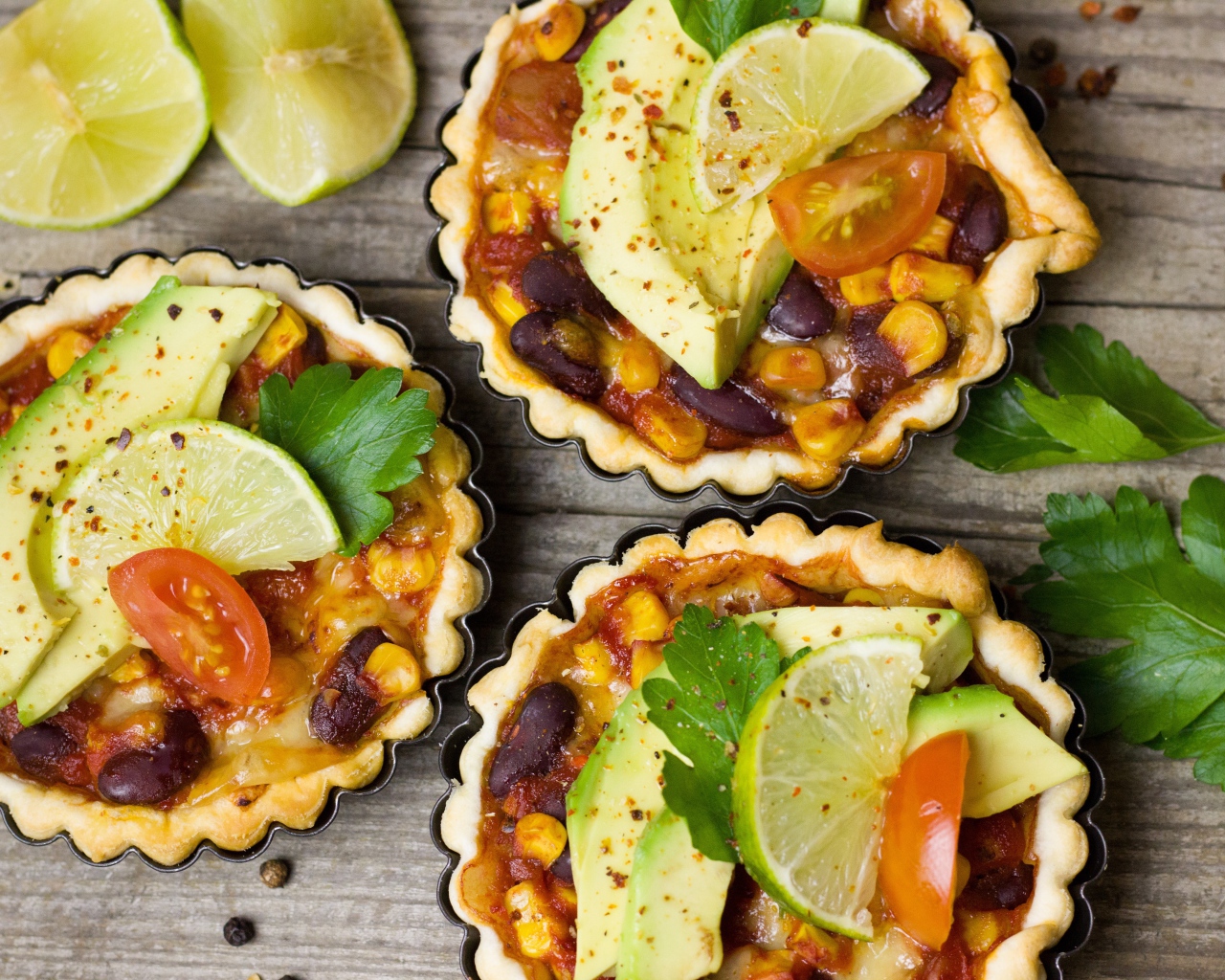 Тарталетки с блюдом, кусочками авокадо и лайма на столе