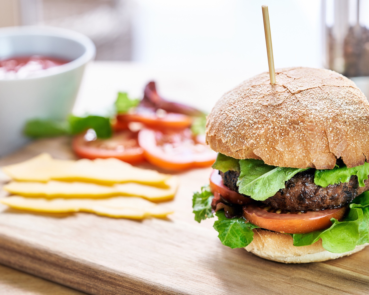 Аппетитный гамбургер на доске с сыром и помидорами