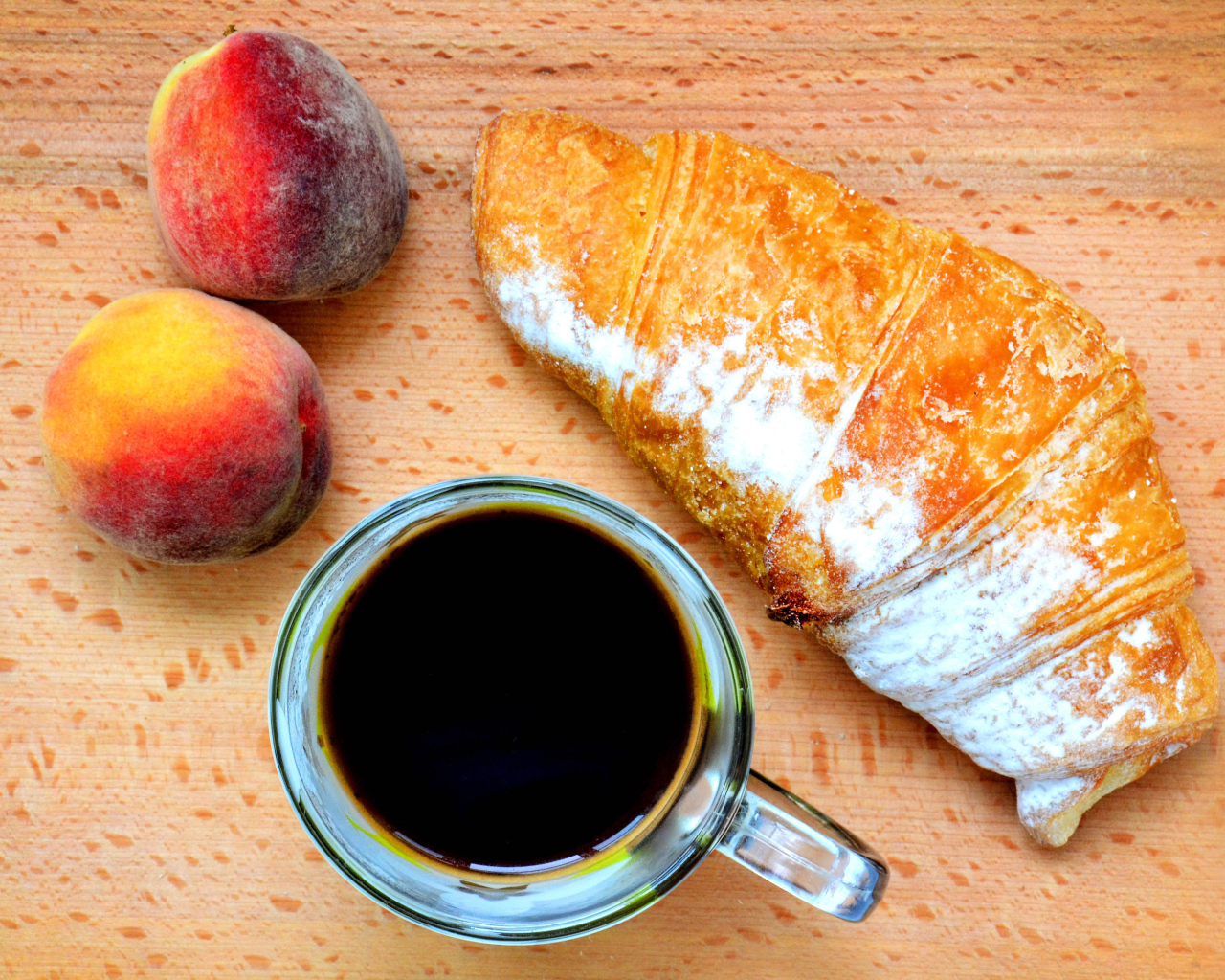 Два персика на столе с кофе и круассаном