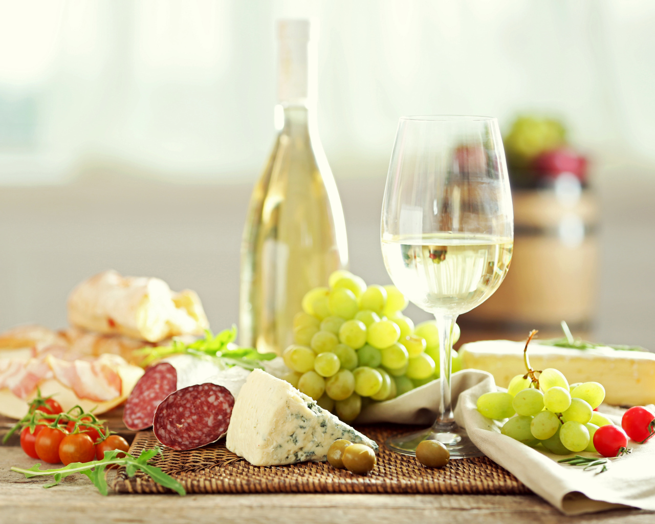 White wine on the table with cheese, sausage and grapes