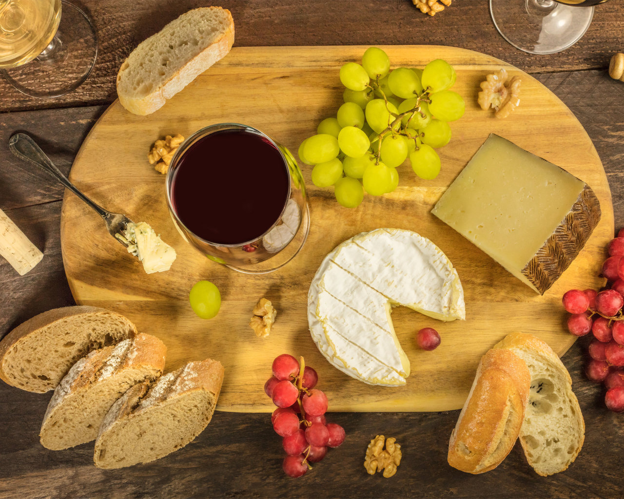 Вино, сыр, виноград и багет на столе 