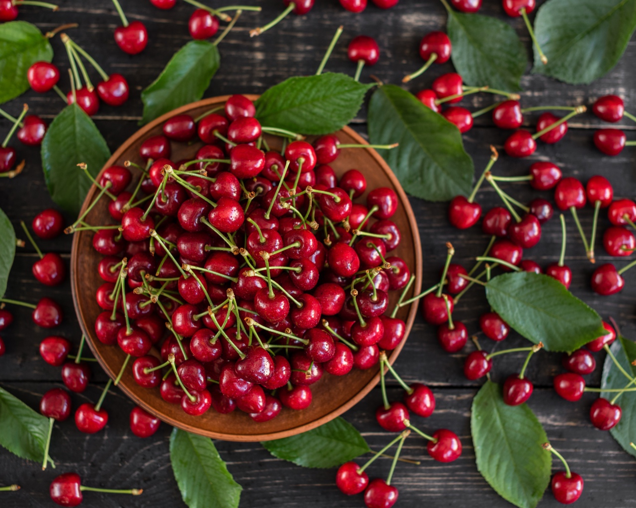 Много спелой красной черешне в миске на столе