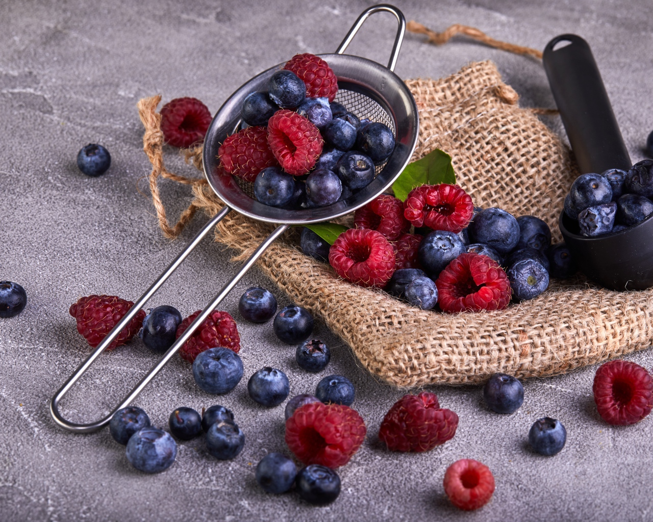 Ягоды черники и малины на столе с ситом