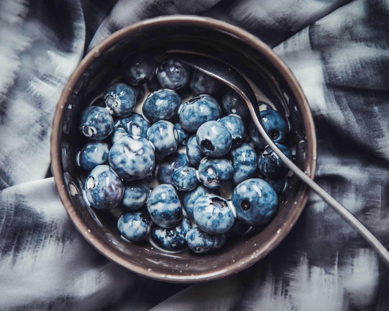 Черника в миске с йогуртом и ложкой