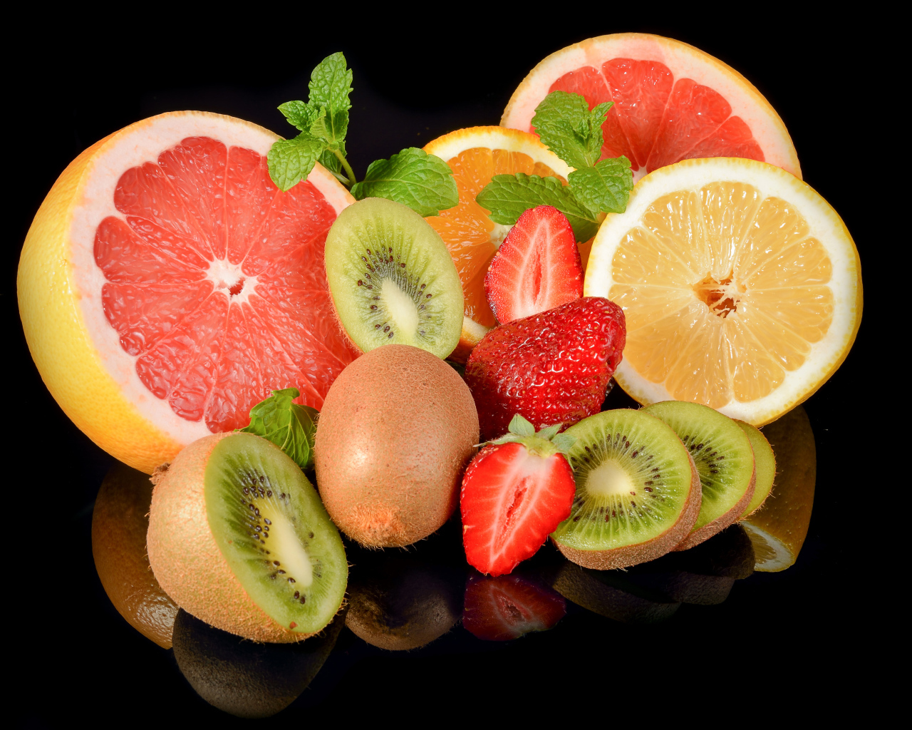 Цитрусовые фрукты на черном фоне с ягодами клубники 