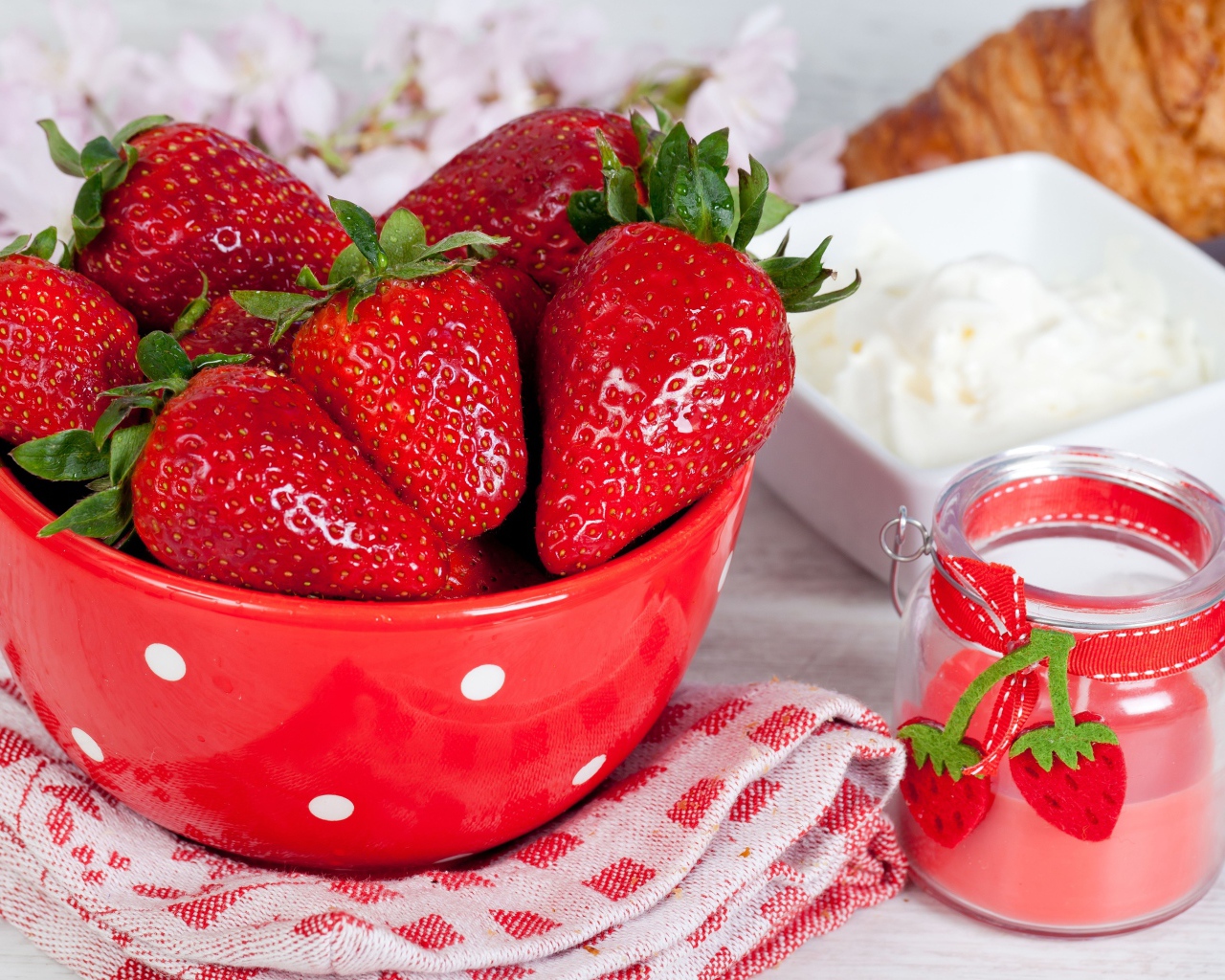 Свежие ягоды клубники в красной миске на столе