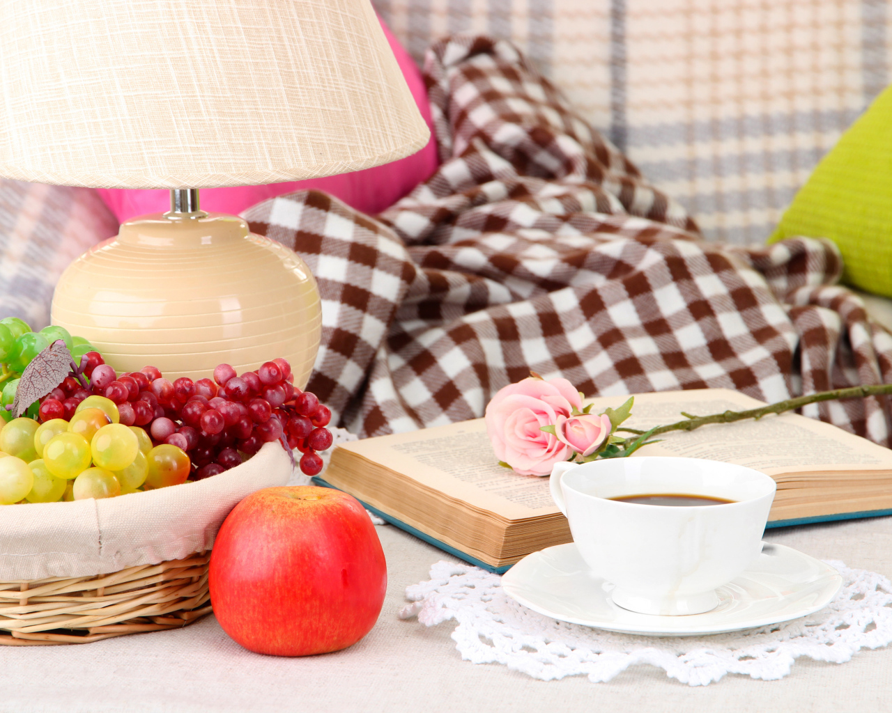 Фрукты в корзине на столе с книгой, чашкой кофе и розой