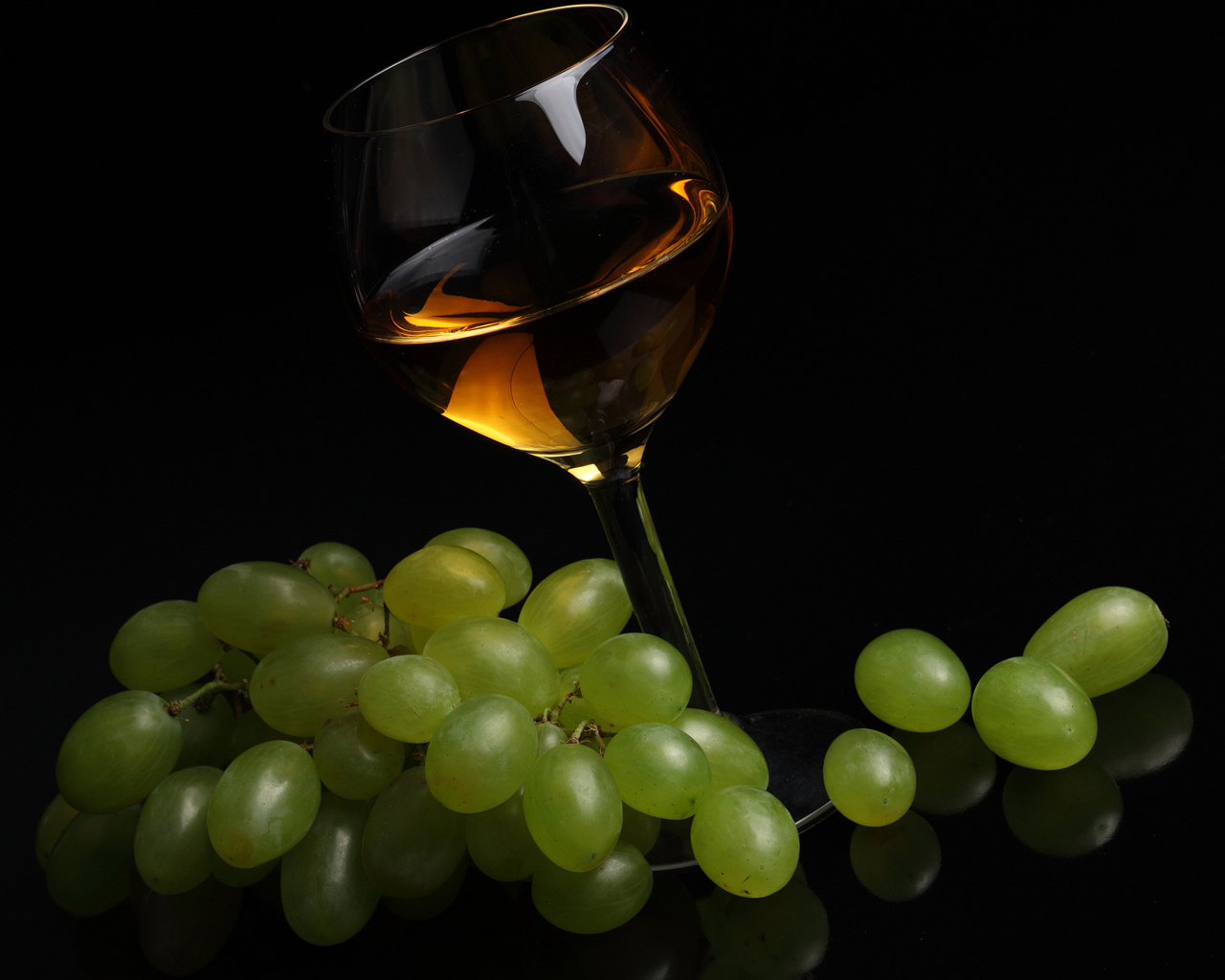 Бокал вина с белым виноградом на черном фоне
