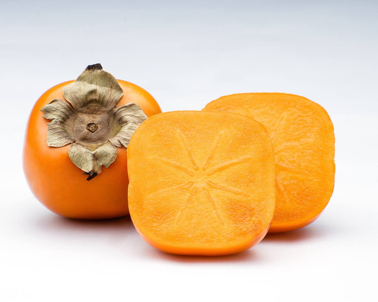 Оранжевая хурма на сером фоне крупным планом