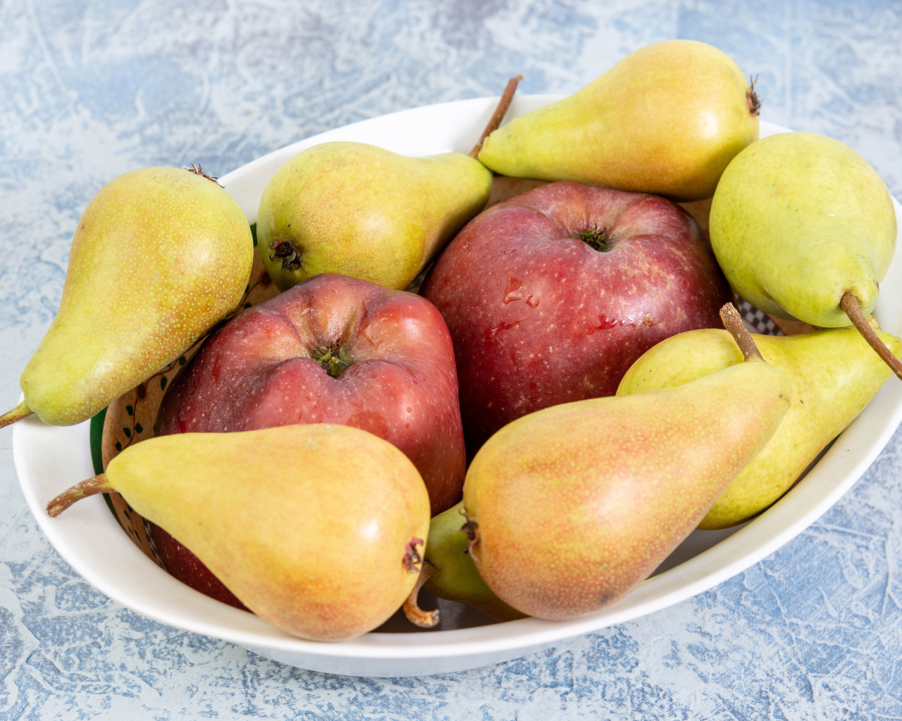 Красные яблок и груши на тарелке на столе