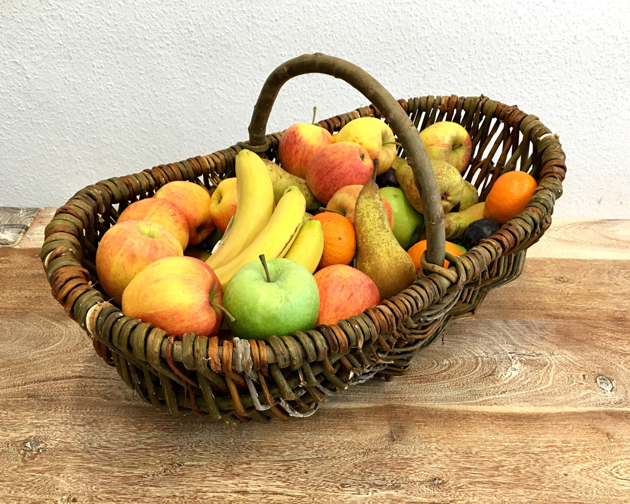 Спелые фрукты в плетеной корзине на столе