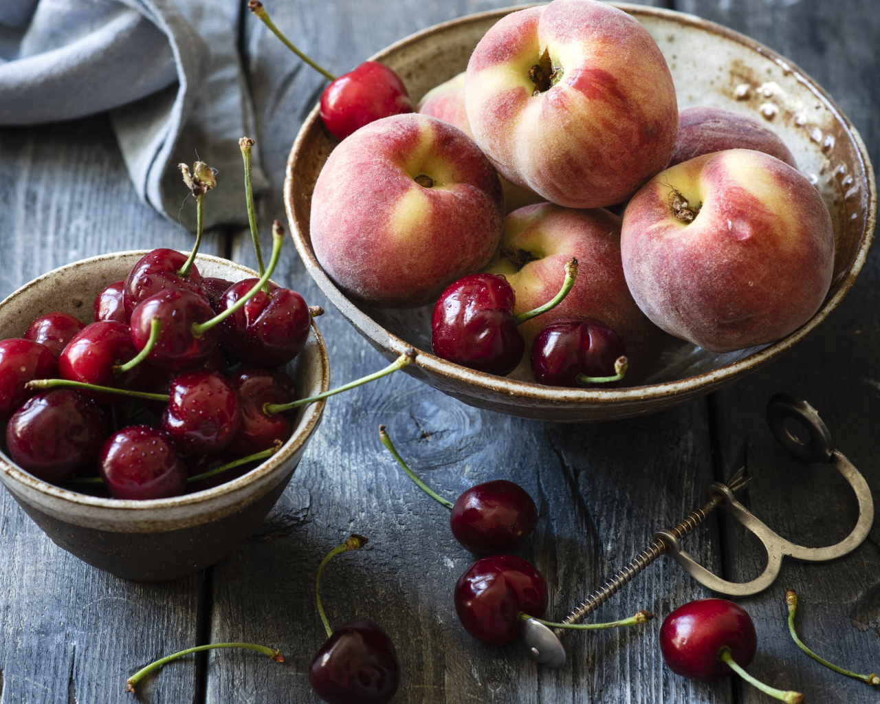 Спелые персики в миске на столе с черешней