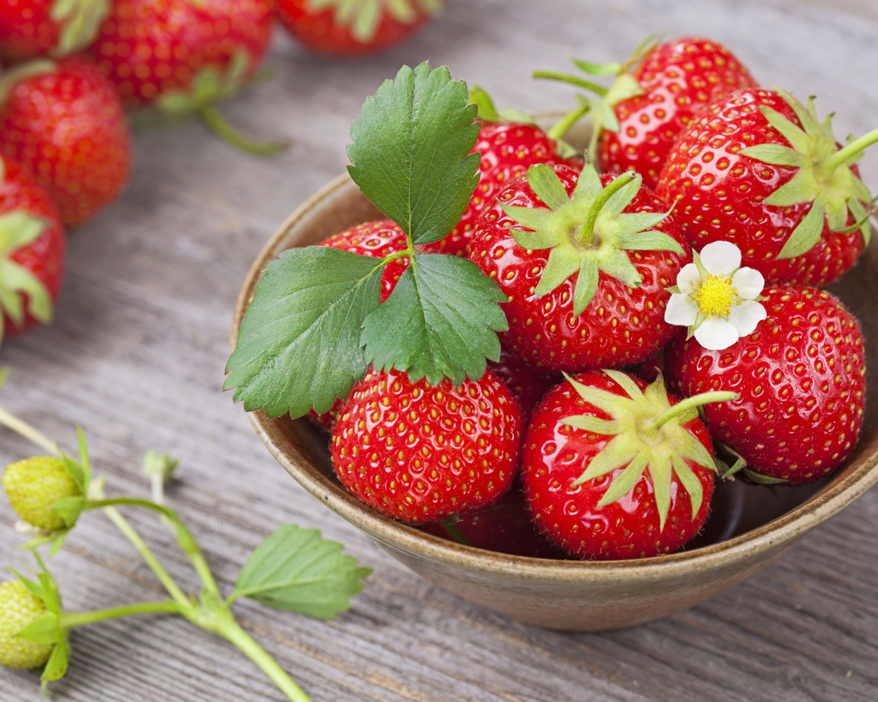 Спелая красная клубника в миске на столе 