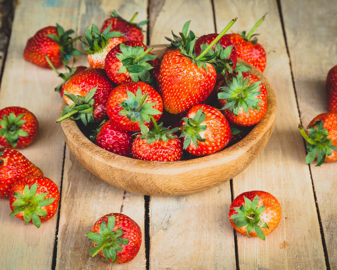 Спелая красная клубника в деревянной миске на столе