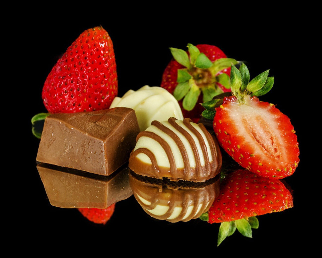 Клубника и шоколадные конфеты на черном фоне