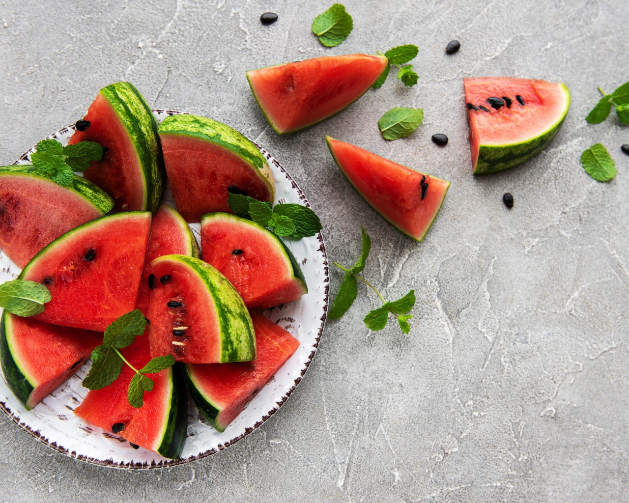 Полосатый арбуз нарезан кусочками на тарелке