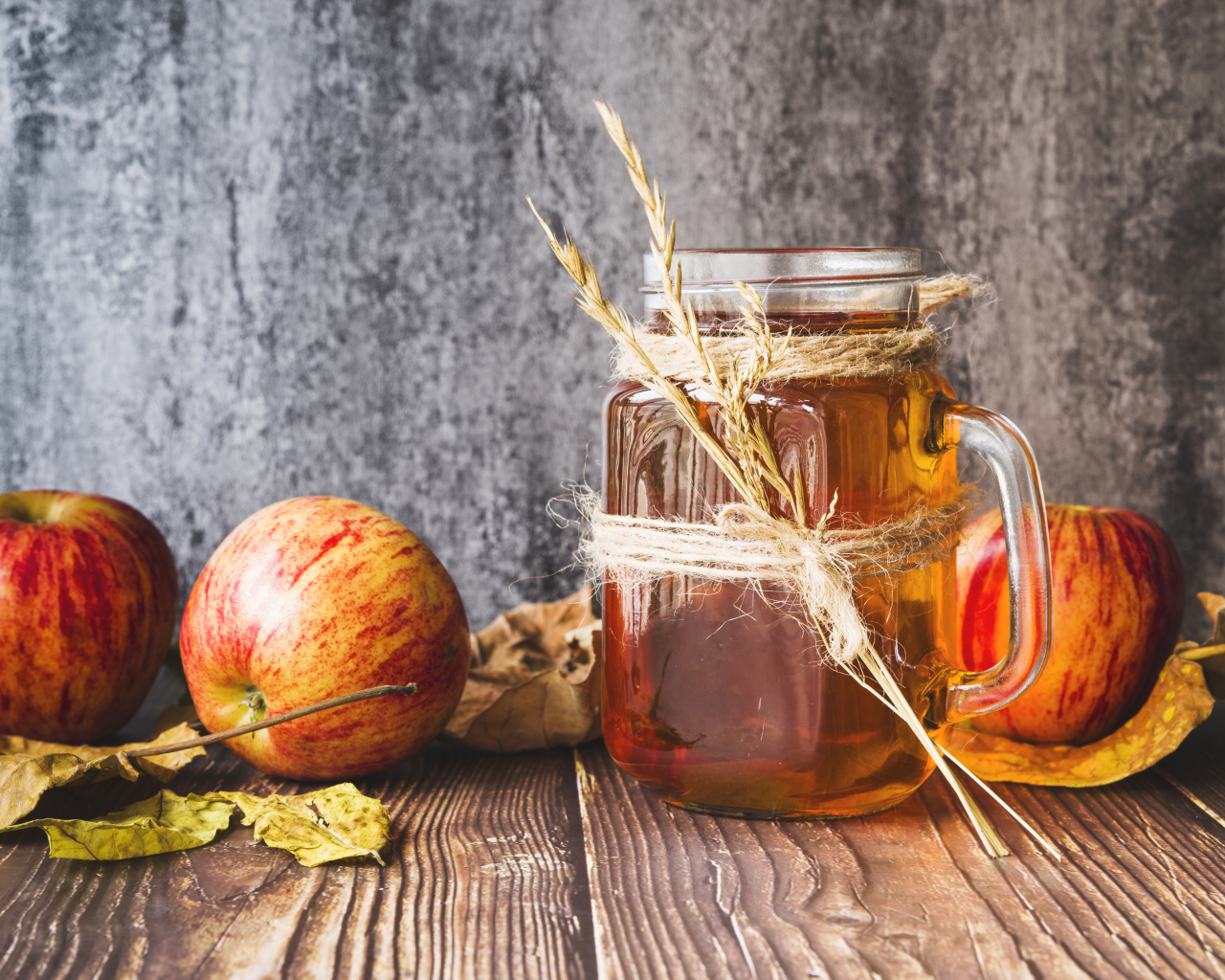 Три яблока с медом на столе на сером фоне