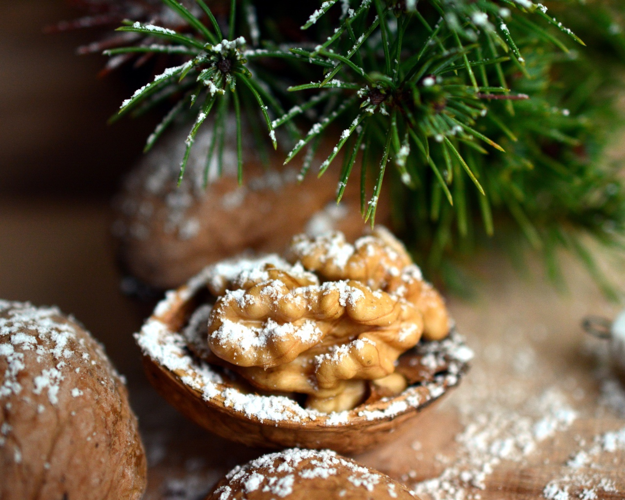 Грецкие орехи посыпанные сахарной пудрой на столе с еловой веткой