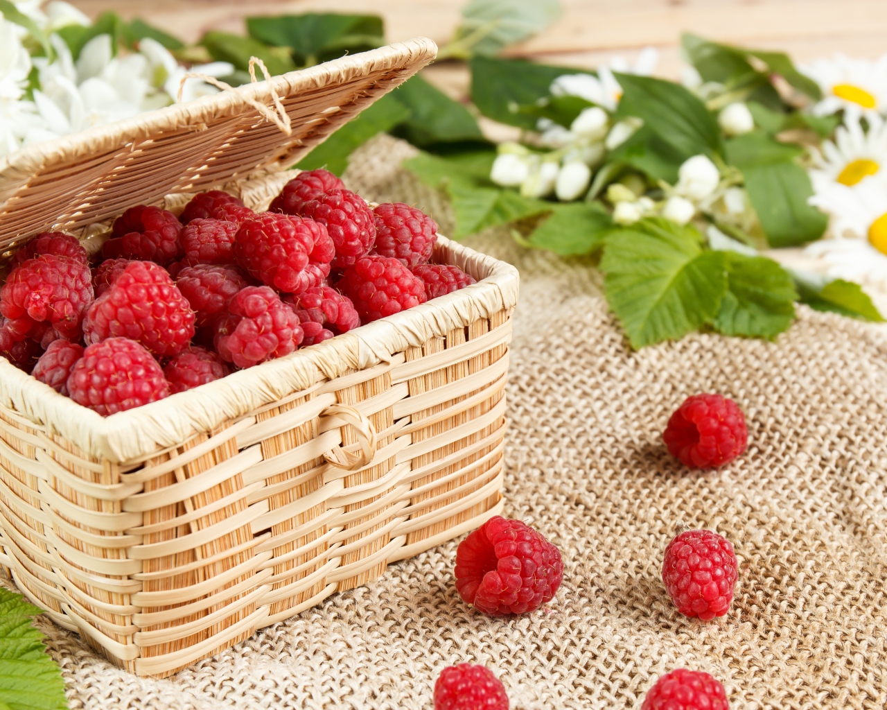 Плетеная корзина на столе с ягодами малины 