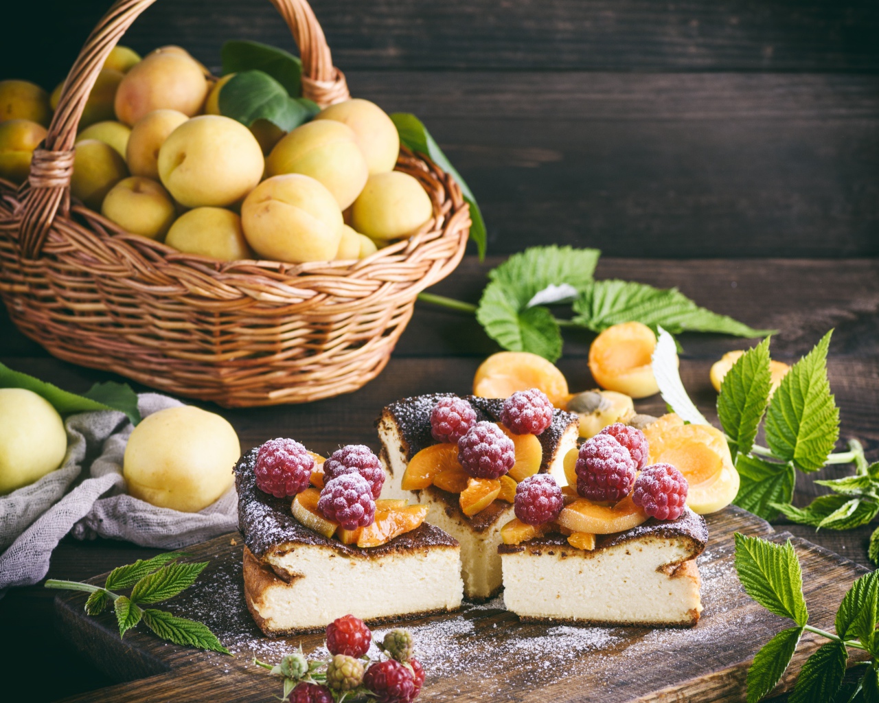 Вкусный фруктово - ягодный пирог на столе с корзиной с абрикосами