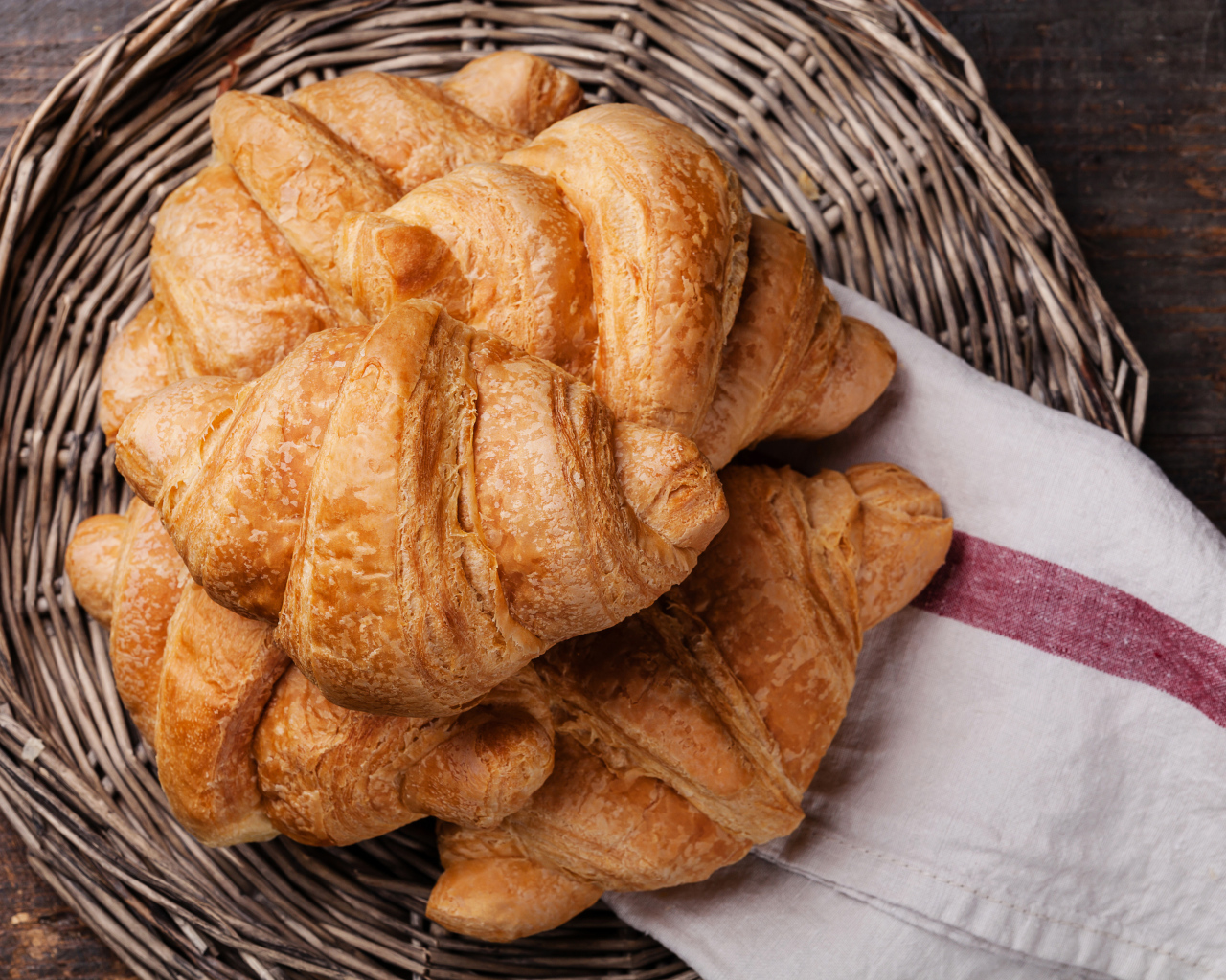 Свежие круассаны в плетеной корзине с полотенцем