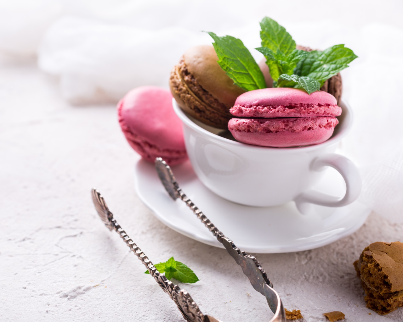 Разноцветный десерт макарун в белой чашке на столе