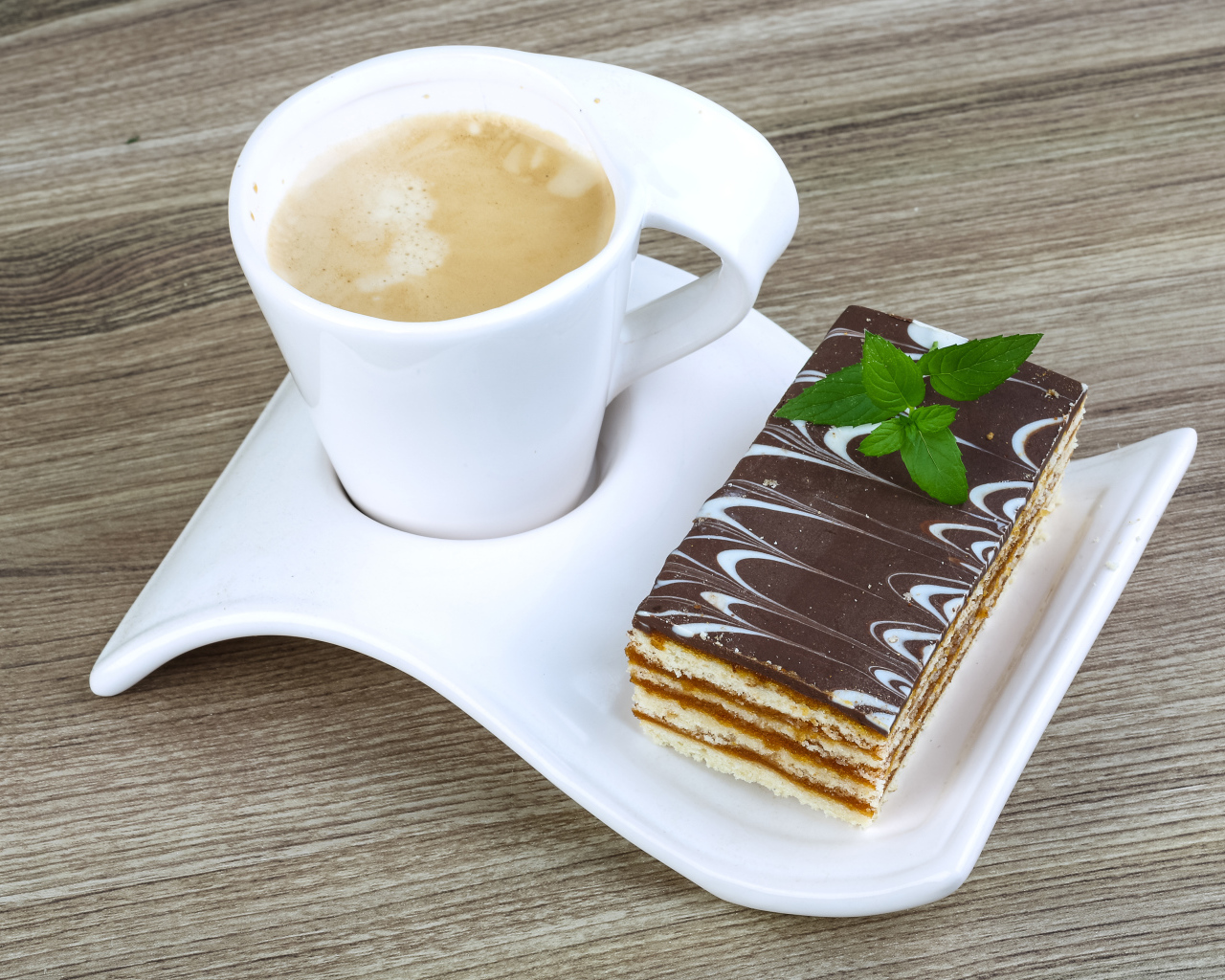 Чашка капучино на тарелке с пирожным 