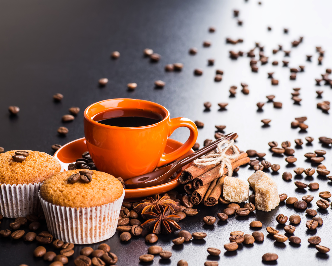 Чашка кофе на столе с кексами, кофейными зернами, корицей и бадьяном
