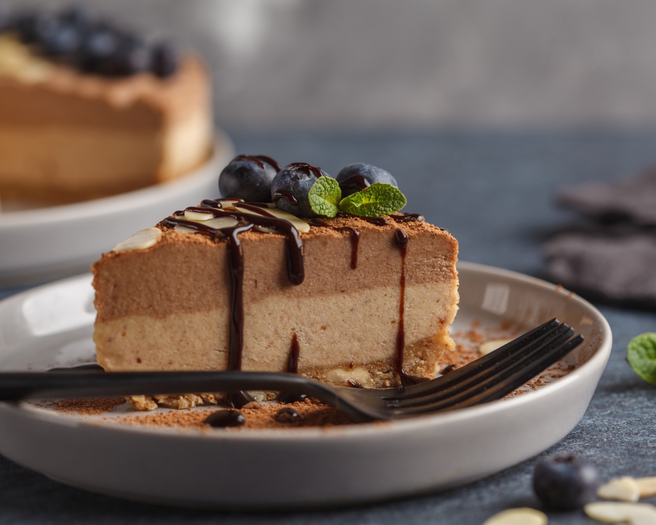 Кусок чизкейка с черникой и шоколадом на тарелке с вилкой