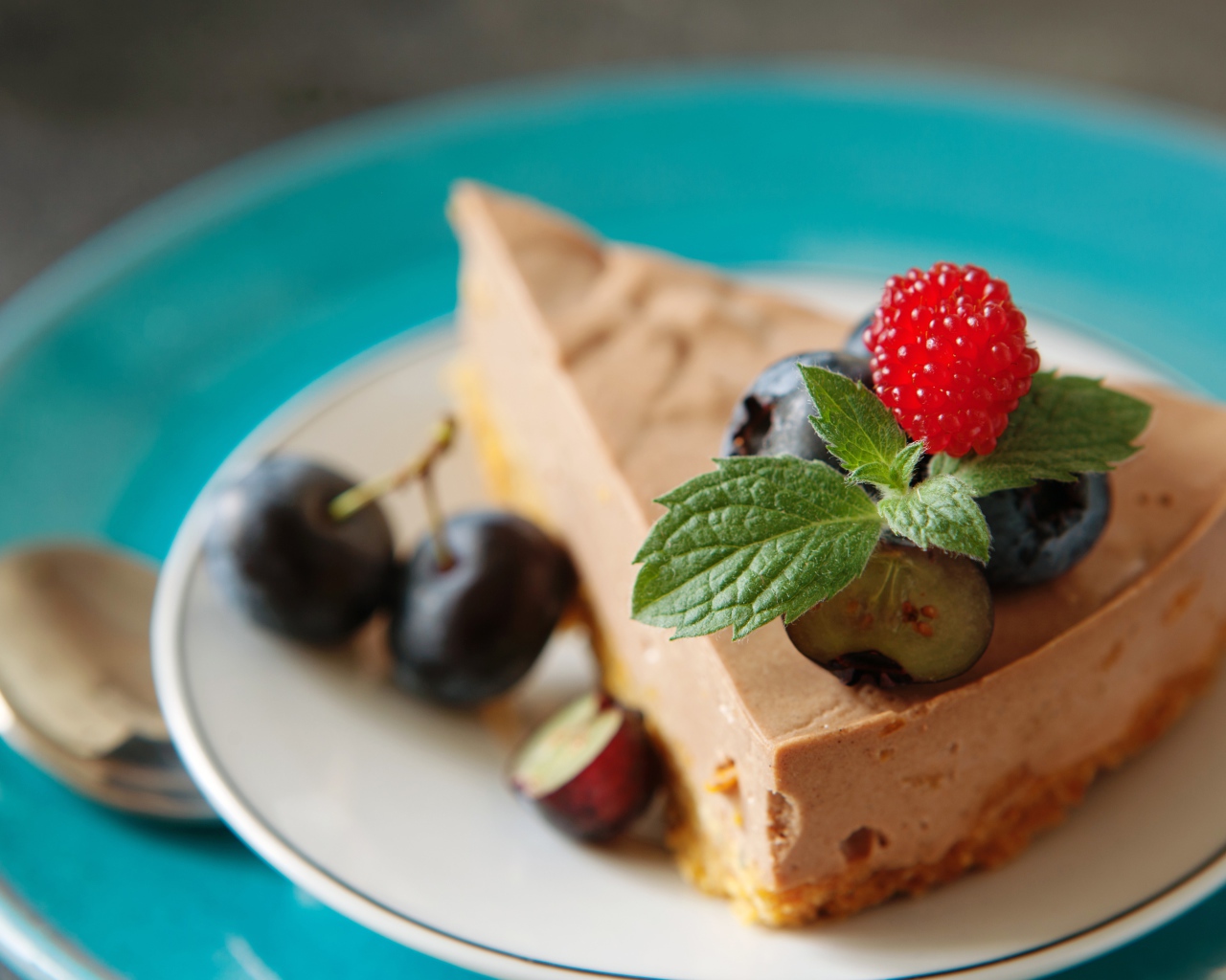 Кусок чизкейка на тарелке с ягодами черники и малиной